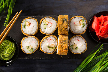 Set of fried sushi rolls with wasabi and ginger on black background. Japanese oriental cuisine