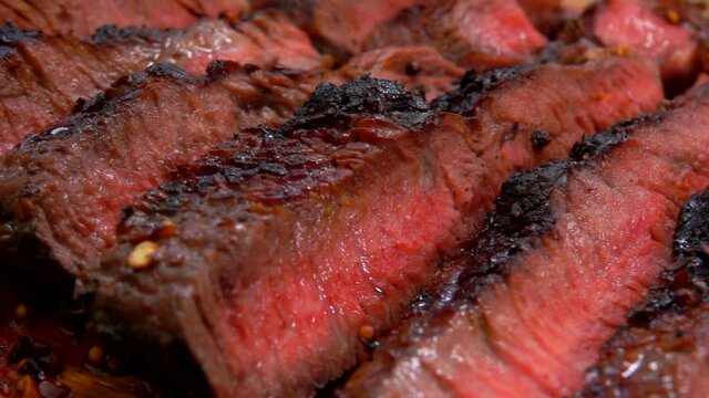 Close-up panorama of Juicy prepared steak cut into slices on a wooden board with fresh vegetables on the background