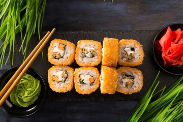Set of fried sushi rolls with wasabi and ginger on black background. Japanese oriental cuisine