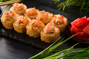 Set of fried sushi rolls with wasabi and ginger on black background. Japanese oriental cuisine