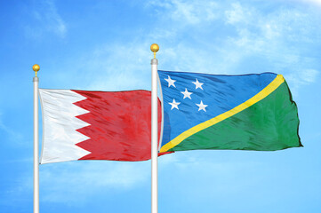 Bahrain and Solomon Islands two flags on flagpoles and blue sky