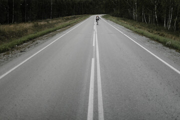 Man in grey office suit with long blond hairs is riding skateboard longboard down road outside the city on front view. Freedom from office work concept.