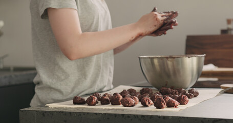 young woman making chocolate truffles on home kictchen
