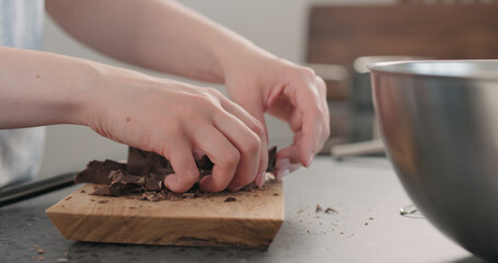 young woman take chocolate chunks from board and put in bowl