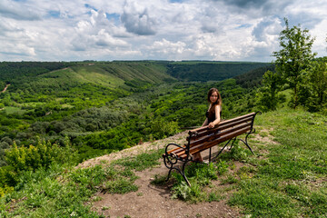 Girl and a beautiful view with a bench on the canyon.