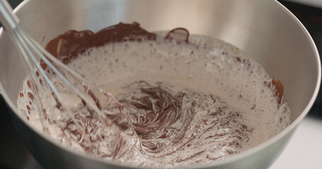 whisking cream with chocolarte in steel bowl