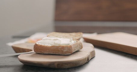 cream cheese over ciabatta to make sandwich on wood board