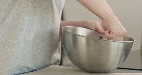 young woman mxing melted chocolate in stainless steel bowl on kitchen