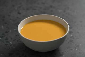 Pumpkin soup in white bowl on concrete background