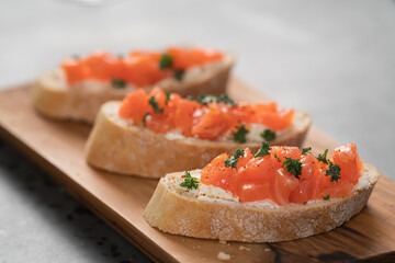 Bruschettas with salmon and cream cheese on olive wood board