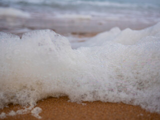 
Foam on the seaside. Sandy beach. Lots of foam on the sea