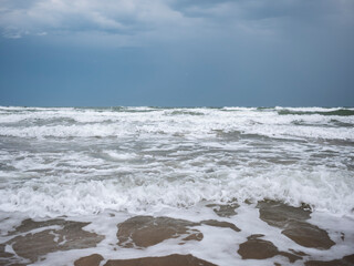 Sea coast. Sandy beach. Lots of foam. Blue sea water. Waves
