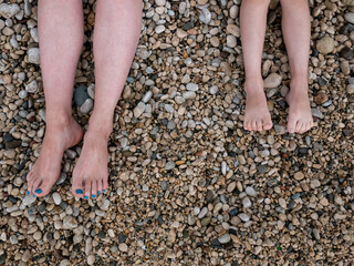 Women's and children's feet on the sea beach. Rest at the sea. Pebbles. Pebble beach