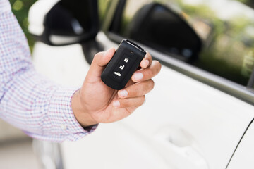 Close up car keys and remote control car alarm systems hold in hand. Young man buy the new car.