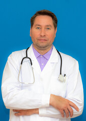 vertical Photo of caucasian brunet hair bristle doc assistant folded hands over chest stand on blue background