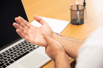 Asian man work so hard and long time that he has office syndrome. He has wrist pain, from working with laptop.