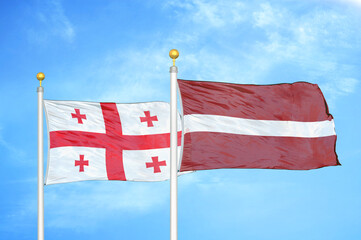 Georgia and Latvia two flags on flagpoles and blue sky