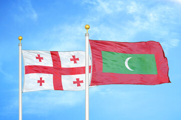 Georgia and Maldives two flags on flagpoles and blue sky