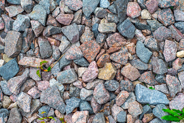 Background with gravel of cranite stones, mostly red granite. Background with stones and rare plant sprouts.