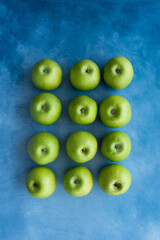 Bright green apples on blue background.