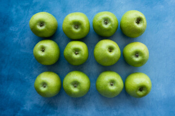 Bright green apples on blue background.