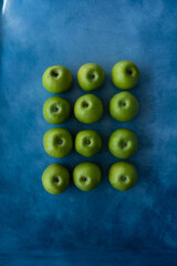 Bright green apples on blue background.