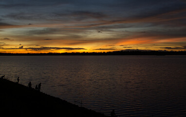 Naklejka premium The silhouette of the lake coast at the sunset.