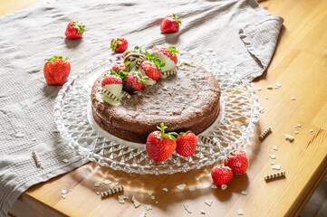 fresh chocolate tart with fresh strawberries and liquid core on a glass plate and wooden table