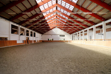 Empty riding hall with sandy covering without riders as an equestrian background