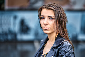 Girl of brunette  in a black leather jacket  on a walk in a cloudy summer evening.