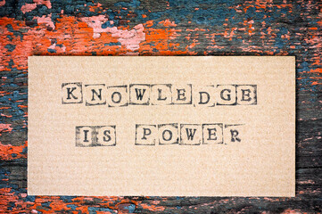 Cardboard with words Knowledge is Power on wooden background.