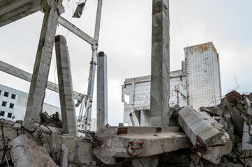 A large ruined building with a pile of gray concrete beams in the foreground. Background