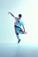 Fototapeta na wymiar Boy dancing in neon light studio. Acrobatic dancer. Stylish flex.