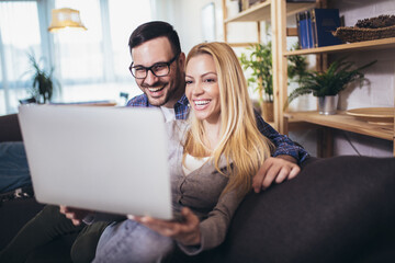 Happy couple communicating while using  laptop at home.