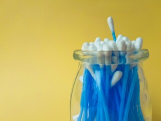 Cotton sticks ear blue plastic on a yellow background. Personal hygiene and care. Cosmetology and medicine.