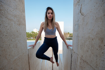 Fit young woman holding herself on her arms, with her feet in the air, above an outdoor stairway.