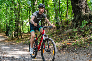 Fototapeta na wymiar Young man biking in forest on red bike
