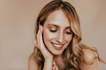 Obraz premium Close-up portrait of pleasant white woman with shiny makeup. Studio photo of chilling blonde girl with beautiful smile.