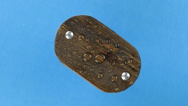 Rotation of a wooden board with water droplets pulsing from the wind.