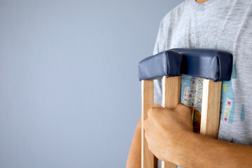 closeup man on crutches on gray with soft-focus and over light in the background