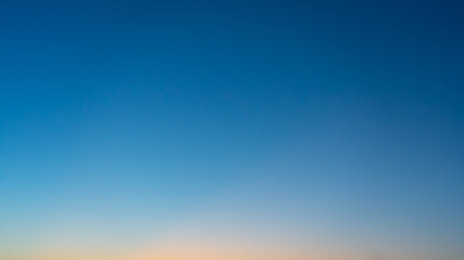 Natural background. The sky before sunrise. The firmament after sunset. Colored smooth transitions from blue to orange. Colorful clear sky with no clouds at dusk after sunset.