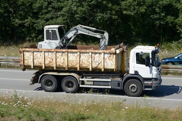 Camion benne avec une pelleteuse roulant sur une voie express en Bretagne