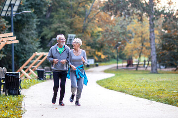 Fototapeta premium Aged couple jogging in the public park and smile