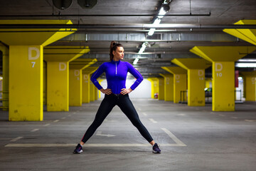 Fototapeta premium Fit girl in sportswear exercise in public garage to stay fit