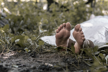 The legs of a corpse lying in the forest. Victim of a crime. Deceased person.