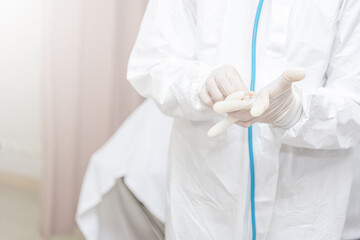 Doctors Surgeon in scrubs putting on surgical gloves. Doctors put on protective glove and mask and suit before proceed patient treatment in hospital in control area. Covid-19 and Coronavirus disease.