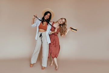 Full-length photo of elegant ladies fooling around on brown background. Carefree girls chilling in...