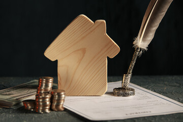 Miniature house with money and tax papers.