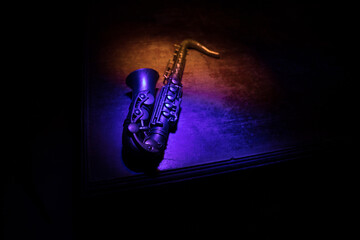 Alto gold sax miniature with colorful toned light on foggy background. Saxophone music instrument in lowlight. Selective focus