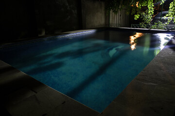 Pool and waterfall at night - vacation background. Colorful light decoration. Freezelight